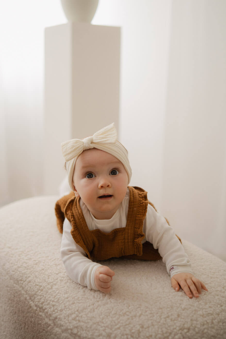 Ein Baby liegt auf dem Bauch und schaut beim Fotoshooting direkt in die Kamera