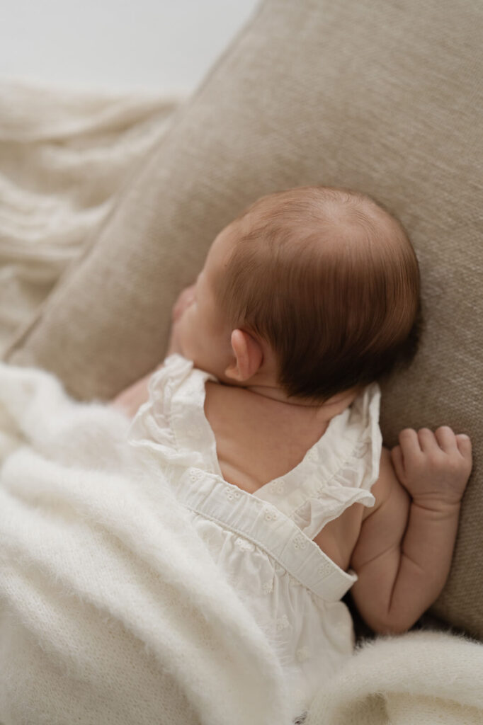Ein Baby schläft auf dem Bauch liegend auf einem Kissen beim Newbornshooting