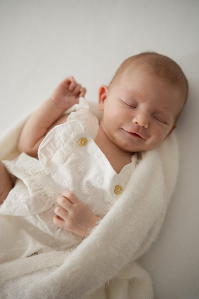 Ein Baby lächelt im Schlaf beim Newbornshooting im Studio von Stefanie Kutzschbach Fotografie in Dachau
