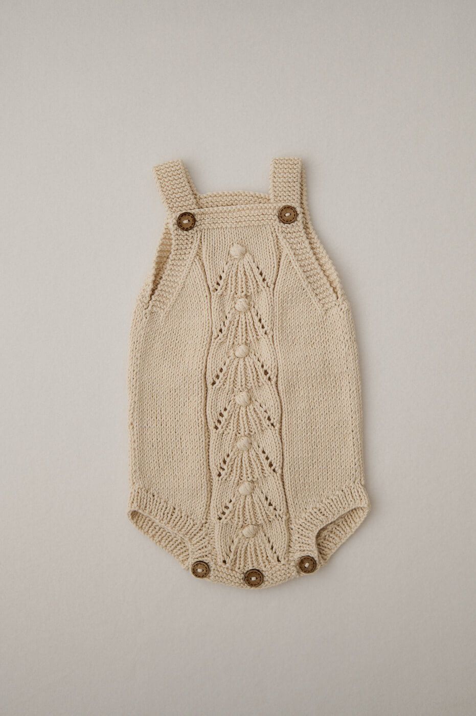 Ein beiger Strampler aus Strick für Newbornshootings