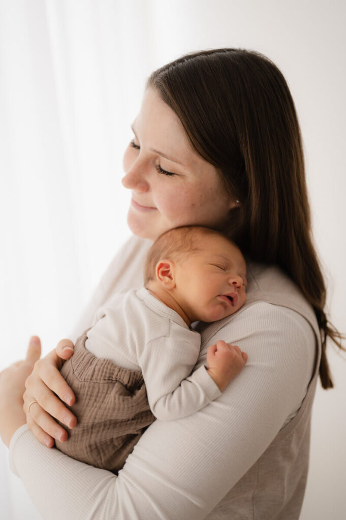 Ein schlafendes Baby liegt auf Mamas Arm beim Newbornshooting im Studio in Dachau.