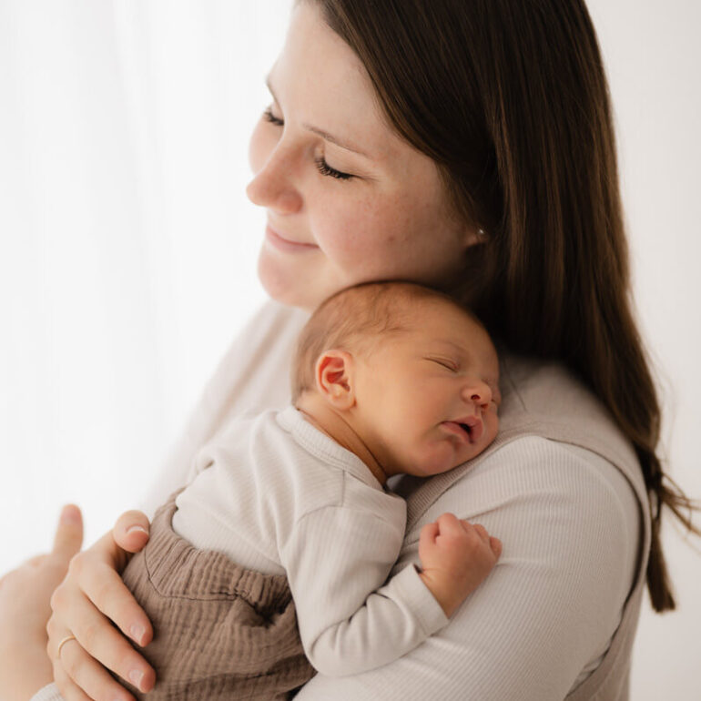 Ein schlafendes Baby liegt auf Mamas Arm beim Newbornshooting im Studio in Dachau.