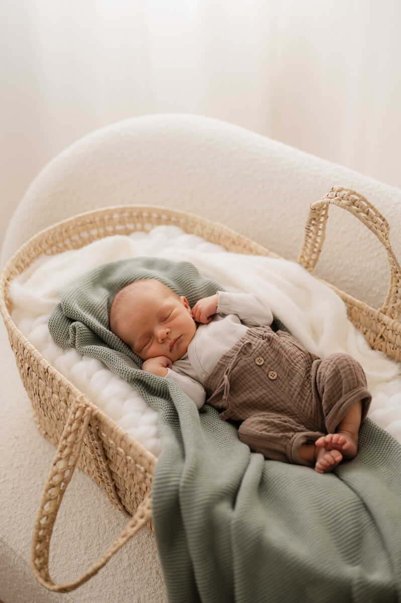 Ein Baby beim Newbornshooting liegt schlafend in einem Rattankörbchen.